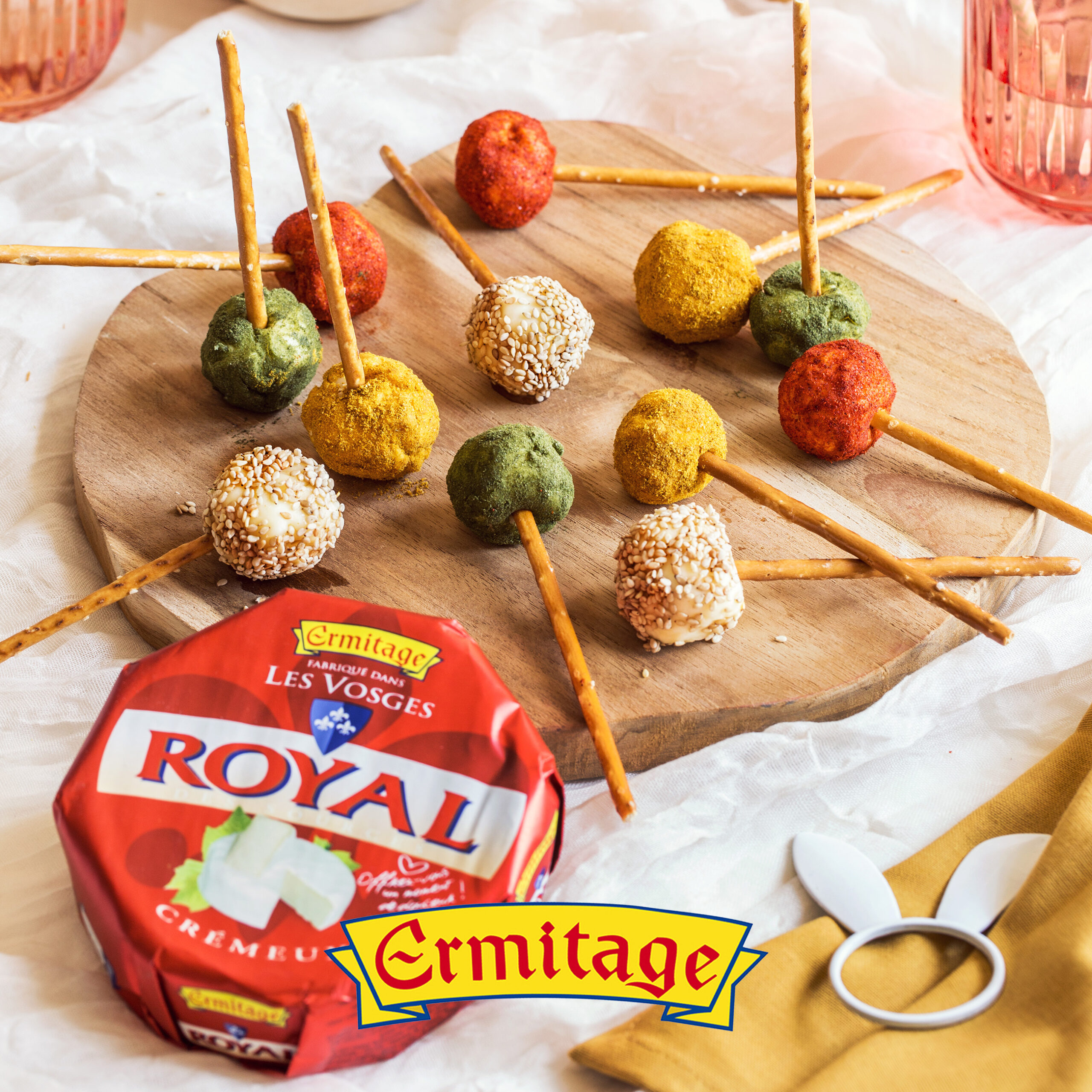 Sucettes apéritives au Royal Crémeux Ermitage, enrobées de toppings colorés (sésame, épices, herbes) avec bâtonnets de bretzel.